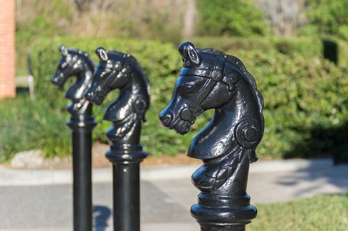 带有马头帽的黑色艺术护柱沿着一条小路排列